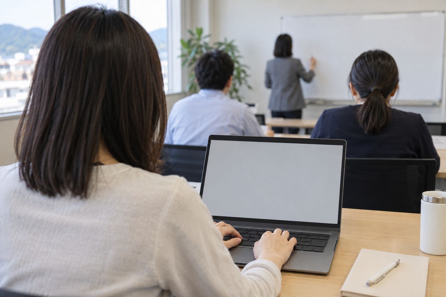 小さな事務所でノートパソコンを開く研修の後ろ姿
